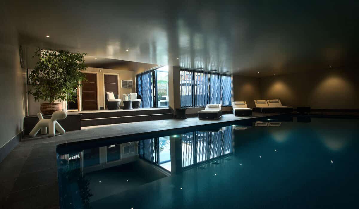 Contemporary basement indoor swimming pool with modern lounge seating and mood lighting.