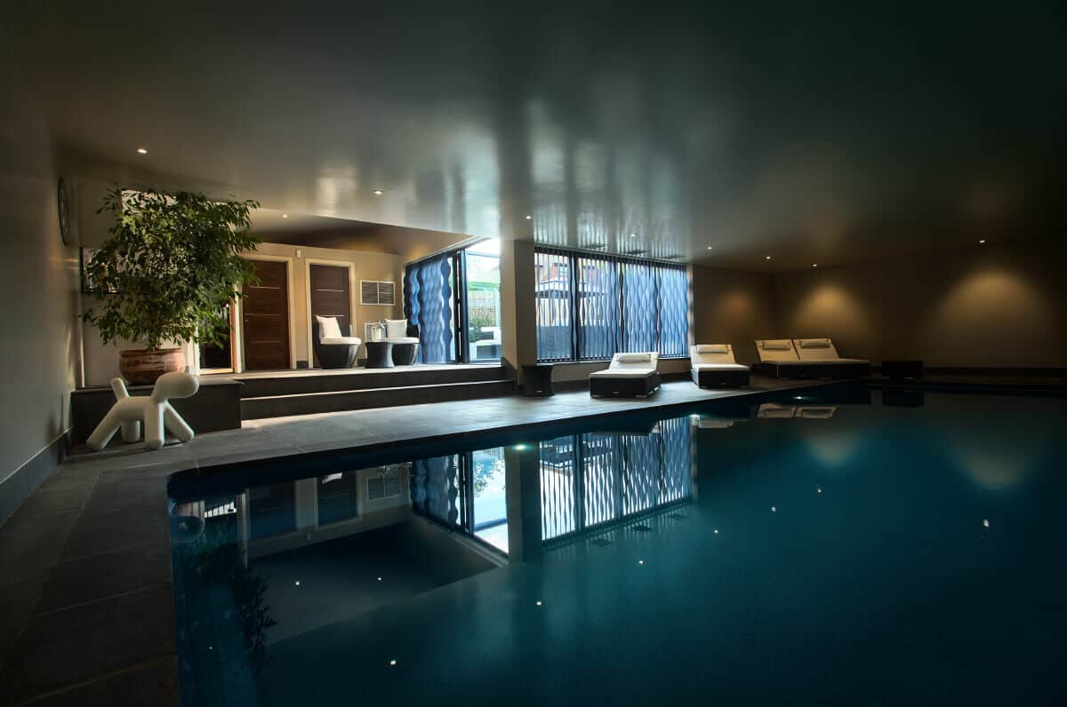 Contemporary basement indoor swimming pool with modern lounge seating and mood lighting.