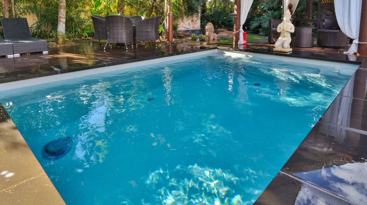 Compact plunge pool in a stylish courtyard setting with seating area and lush tropical landscaping.