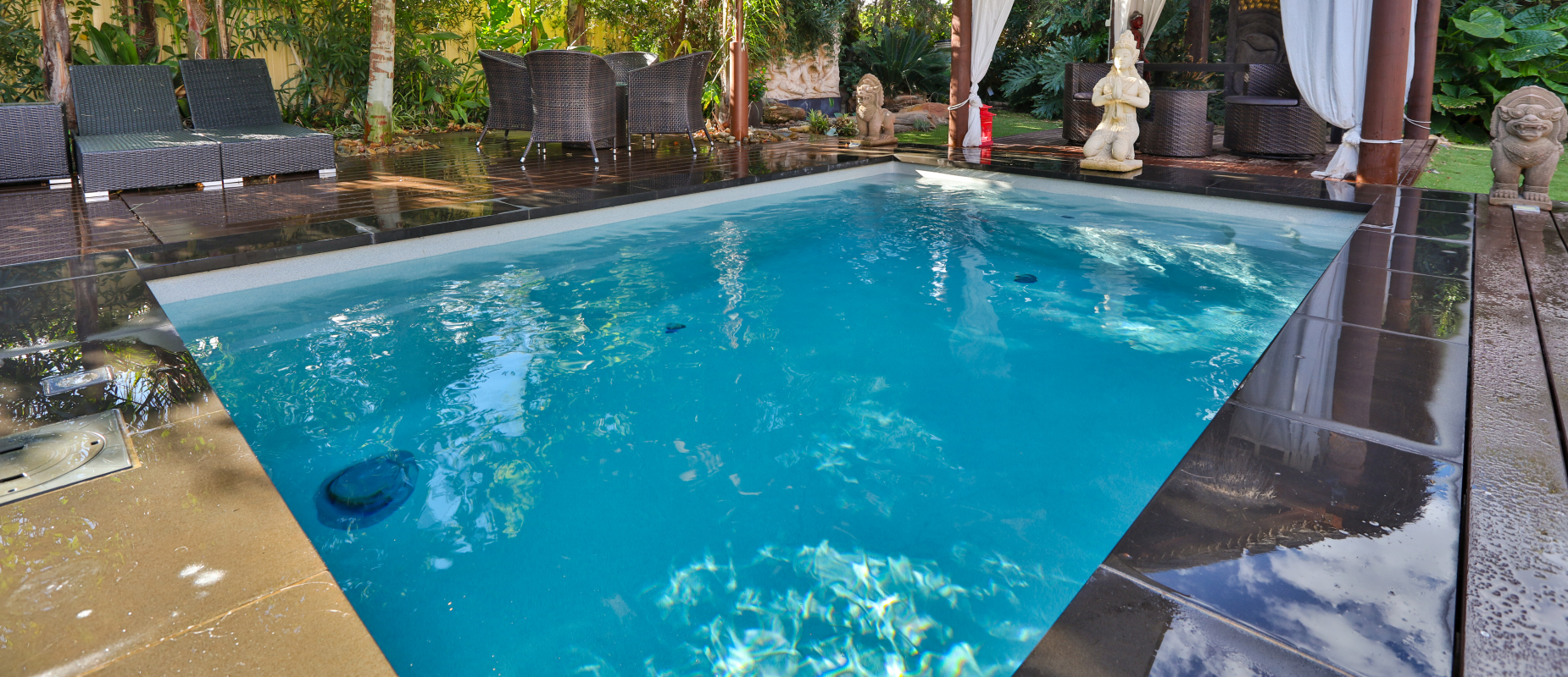 Compact plunge pool in a stylish courtyard setting with seating area and lush tropical landscaping.