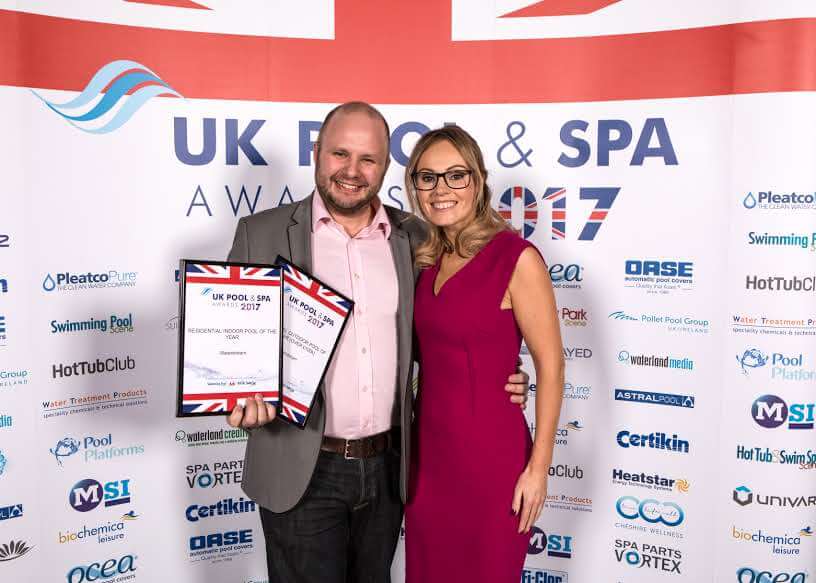 Two people posing with UK Pool & Spa Awards 2017 certificates at an awards ceremony.
