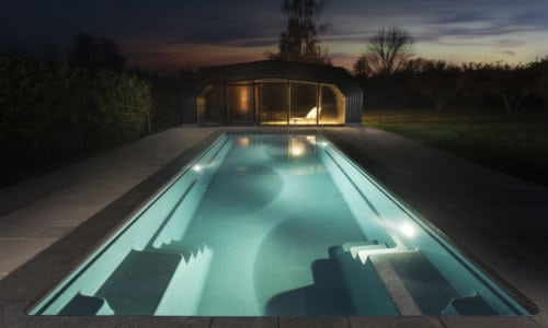 Contemporary outdoor swimming pool illuminated by soft LED lighting.